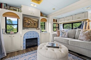 Ein gemütliches Wohnmobil-Interieur mit Kamin, einer Sitzecke und einem Buch mit dem Titel 'The Horse Encyclopedia'.