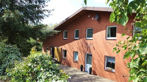A brick building with multiple windows, a door, and potted plants on the windowsills. - Zwei Ferienwohnungen in Kirchdorf (Kirchdorf)