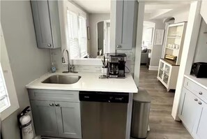 Una cocina equipada con lavavajillas, cafetera y cubo de basura.
