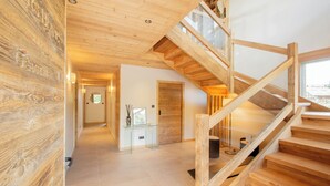 Eine Holztreppe mit Glastrennläufern führt zu einer oberen Ebene, einem Flur mit einem Glastisch und einer Holzwand.