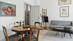 Un comedor con una mesa y sillas de madera, un sofá gris y obras de arte en las paredes.