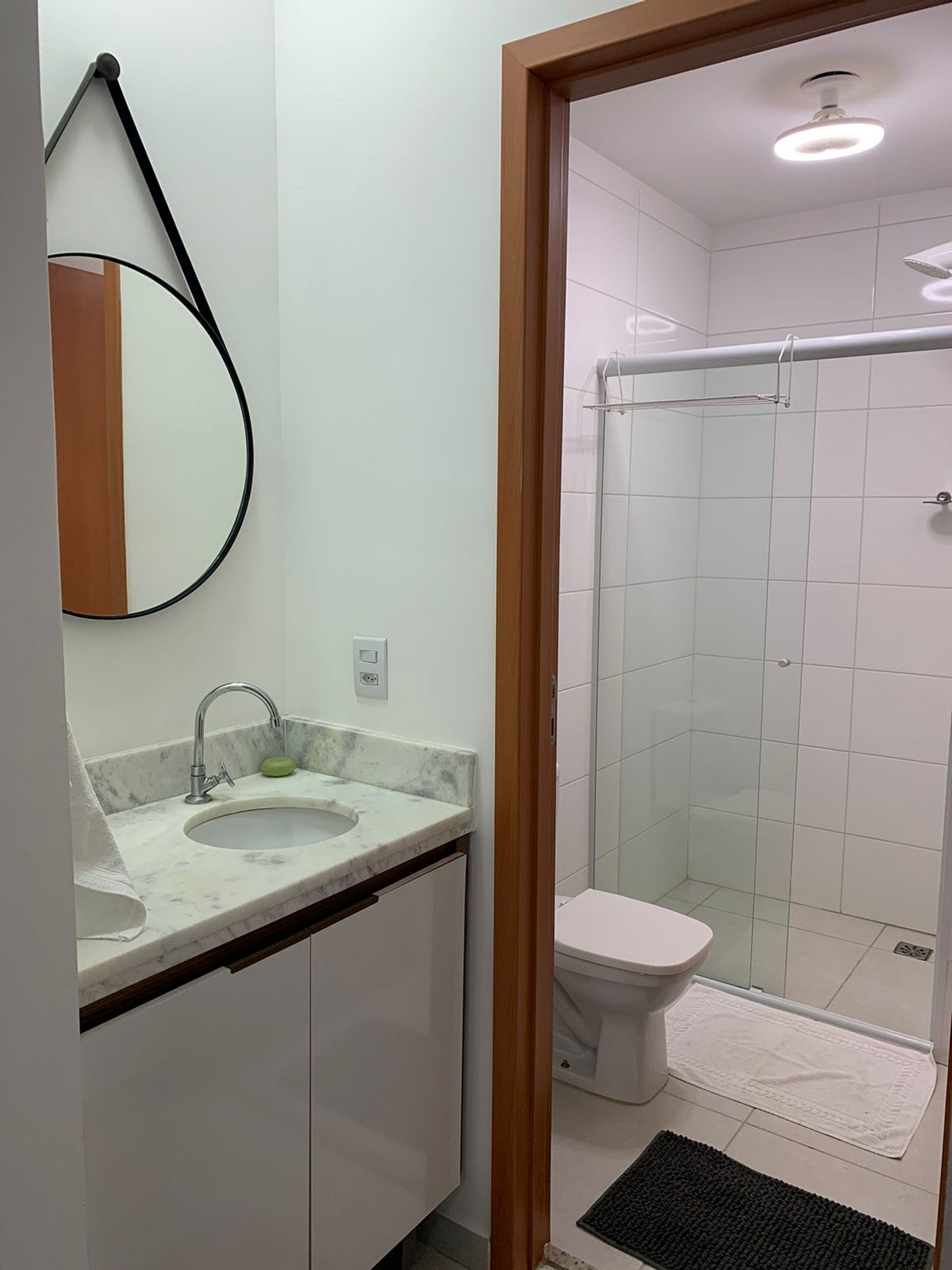 A bathroom with a sink, mirror, toilet, and shower.