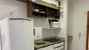 A kitchen with a refrigerator, microwave, gas stove, and cabinets. - Oceana Suites Cachoeira Paulista (Cachoeira Paulista)