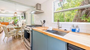 A modern kitchen with a large window, a dining area with wicker chairs, and a built-in stove. - The Flamingo House - Sarasota (Sarasota)