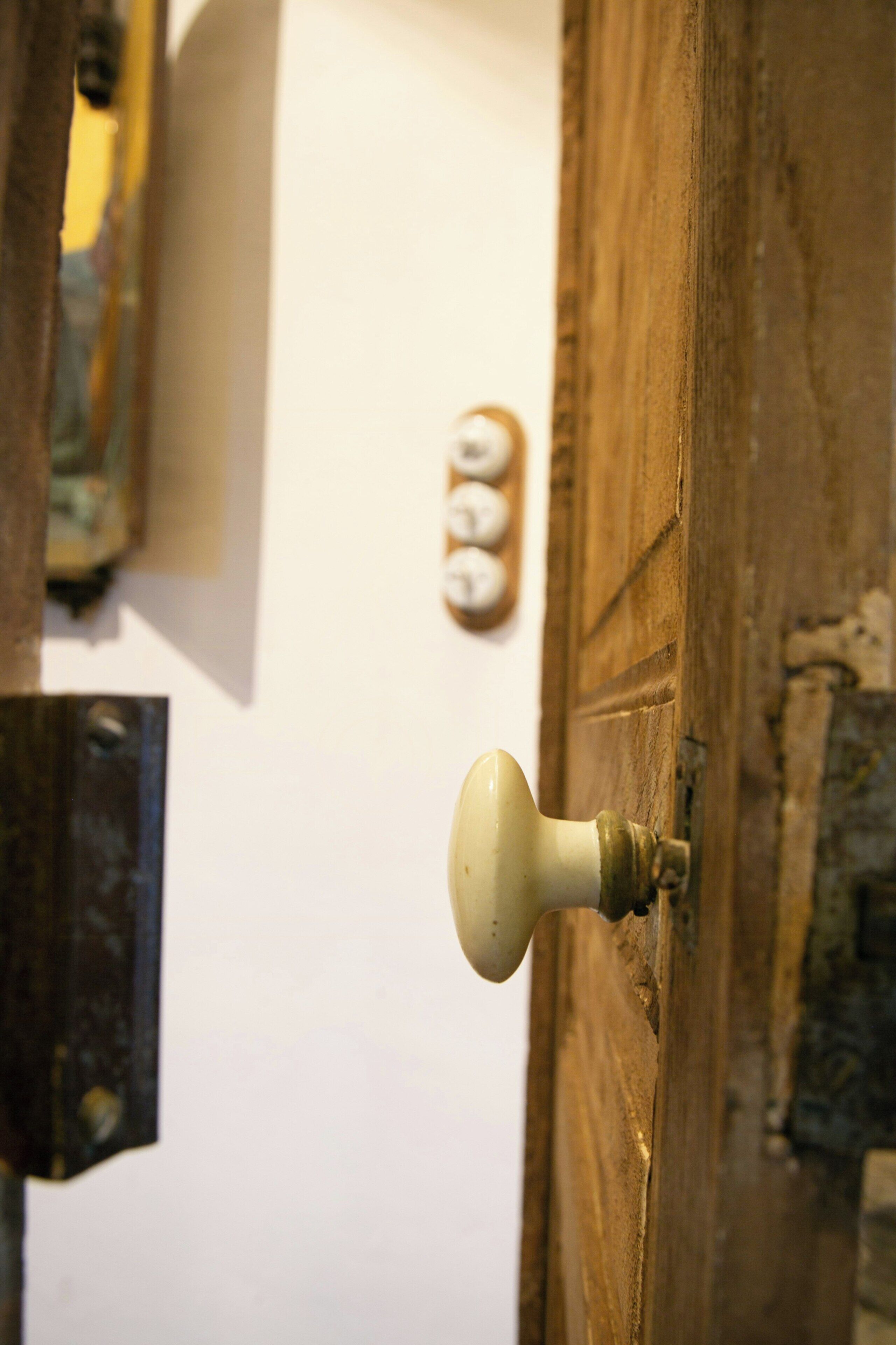 Una puerta de madera con un pomo redondo, un reloj de pared y un interruptor de luz.
