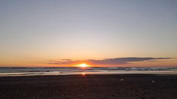 Una playa al atardecer, con el sol poniéndose en el horizonte.