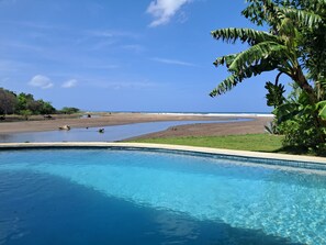 Une piscine d’un bleu éclatant, avec vue sur une plage et l’océan.