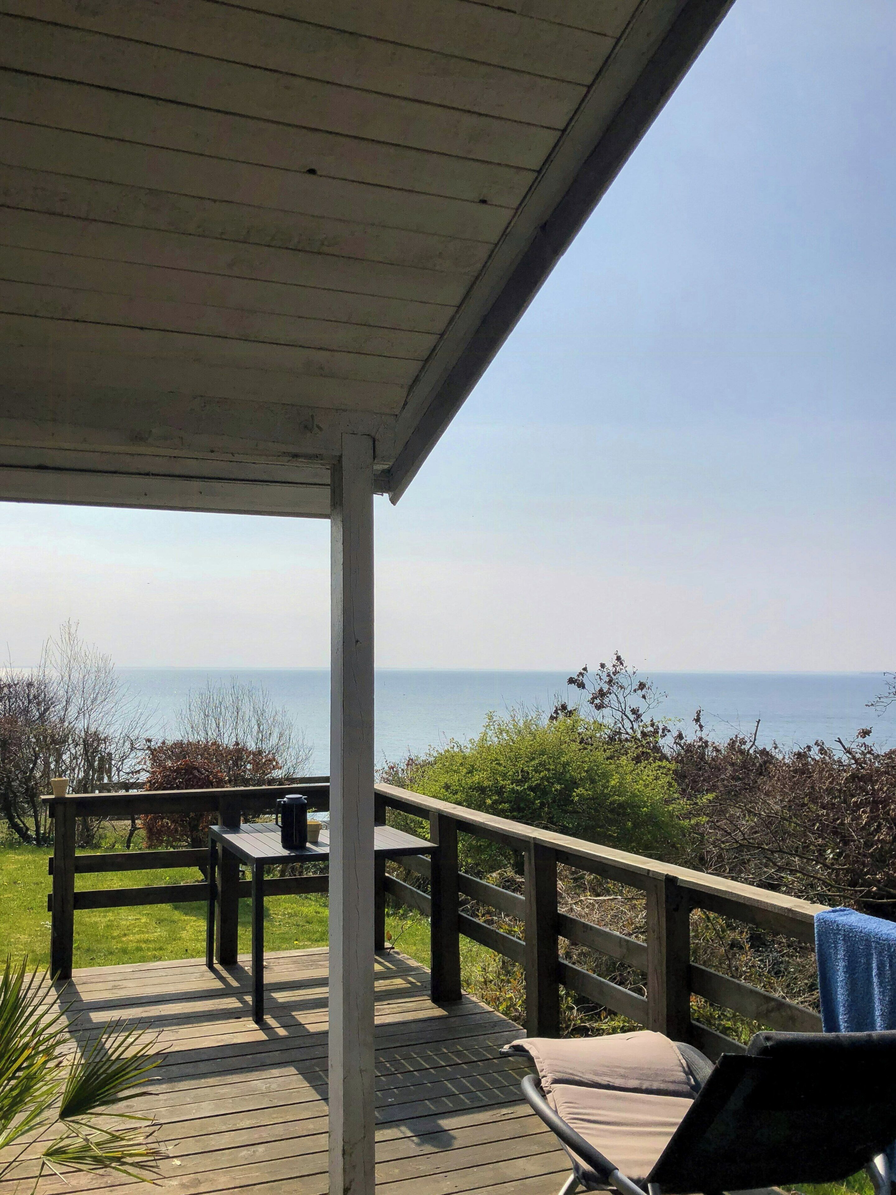 A wooden deck with a table and chairs, overlooking a body of water.