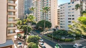 Un hôtel à plusieurs étages doté de balcons, d’un parking et de palmiers.