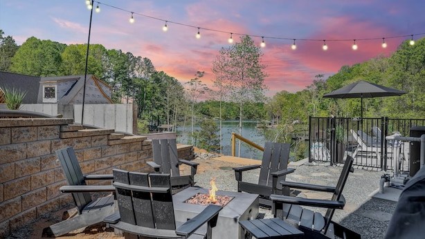 An outdoor patio with Adirondack chairs, a fire pit, and string lights against a sunset backdrop. - Stillwater Overlook (Bedford County)