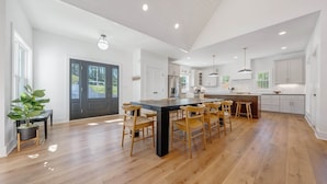 A spacious kitchen with a central island, wooden chairs, and a large window. - Stillwater Overlook (Bedford County)