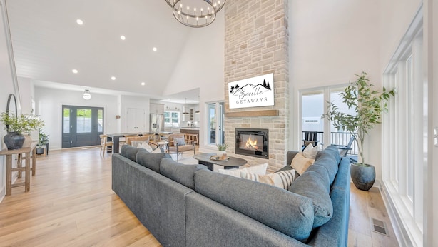 A spacious living area with a fireplace, a large sofa, and a dining area with a kitchen in the background. - Watermark Bluff (Bedford County)