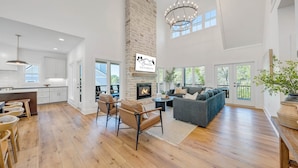 A spacious living area with a fireplace, a dining area with stools, and a large window overlooking greenery. - Watermark Bluff (Bedford County)