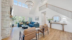 A spacious living area with a sectional sofa, leather chairs, a wooden coffee table, and a chandelier. - Watermark Bluff (Bedford County)