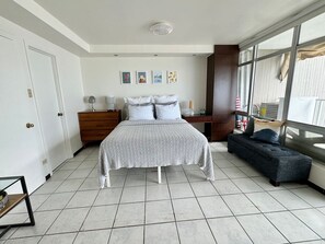 A bedroom with a bed, bedside tables, a dresser, a window, and a balcony. - Charming Isla Verde with Pool & Beach Access (Carolina)