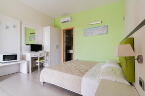 Un dormitorio con cama, escritorio, silla, televisión y armario.