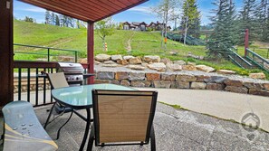 Eine Terrasse im Freien mit Grill, Sitzgelegenheit und einer Steinmauer.