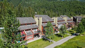 Un conjunto de edificios con techos rojos y balcones, rodeado de vegetación y montañas.