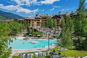 Ein Resort mit großem Außenpool, mehreren Gebäuden mit Balkonen und einer Bergkulisse.
