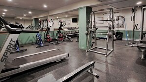 Un gimnasio con cintas de correr, máquinas elípticas y equipo de levantamiento de pesas.