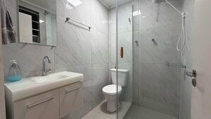 A bathroom with a glass-enclosed shower, a white sink, a toilet, and a mirror above the sink. - Downtown Florianópolis, everything nearby, comfortable, fully equipped, 4 bedrooms with AC and 2 bathrooms. (Florianópolis)