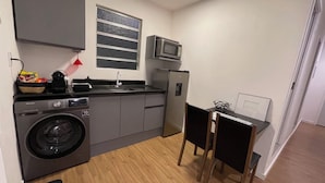 A compact kitchen with a washing machine, a microwave, and a refrigerator. - Downtown Florianópolis, everything nearby, comfortable, fully equipped, 4 bedrooms with AC and 2 bathrooms. (Florianópolis)
