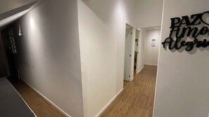 Ein Flur mit weißen Wänden und Holzböden, der zu einem Raum mit einer Tür führt.