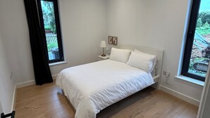 Una camera da letto con un letto, una finestra, un comodino e una porta.