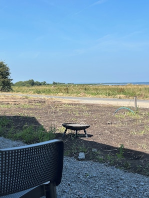 A gravel area with a metal table and a bench, a grassy field with cows, and a clear sky. - Modern Rural Ireland Retreat – Spacious & Peaceful Countryside Escape. (Derryadd)