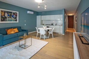 Eine moderne Wohnung mit Wohnbereich, Essplatz und Küchenzeile.