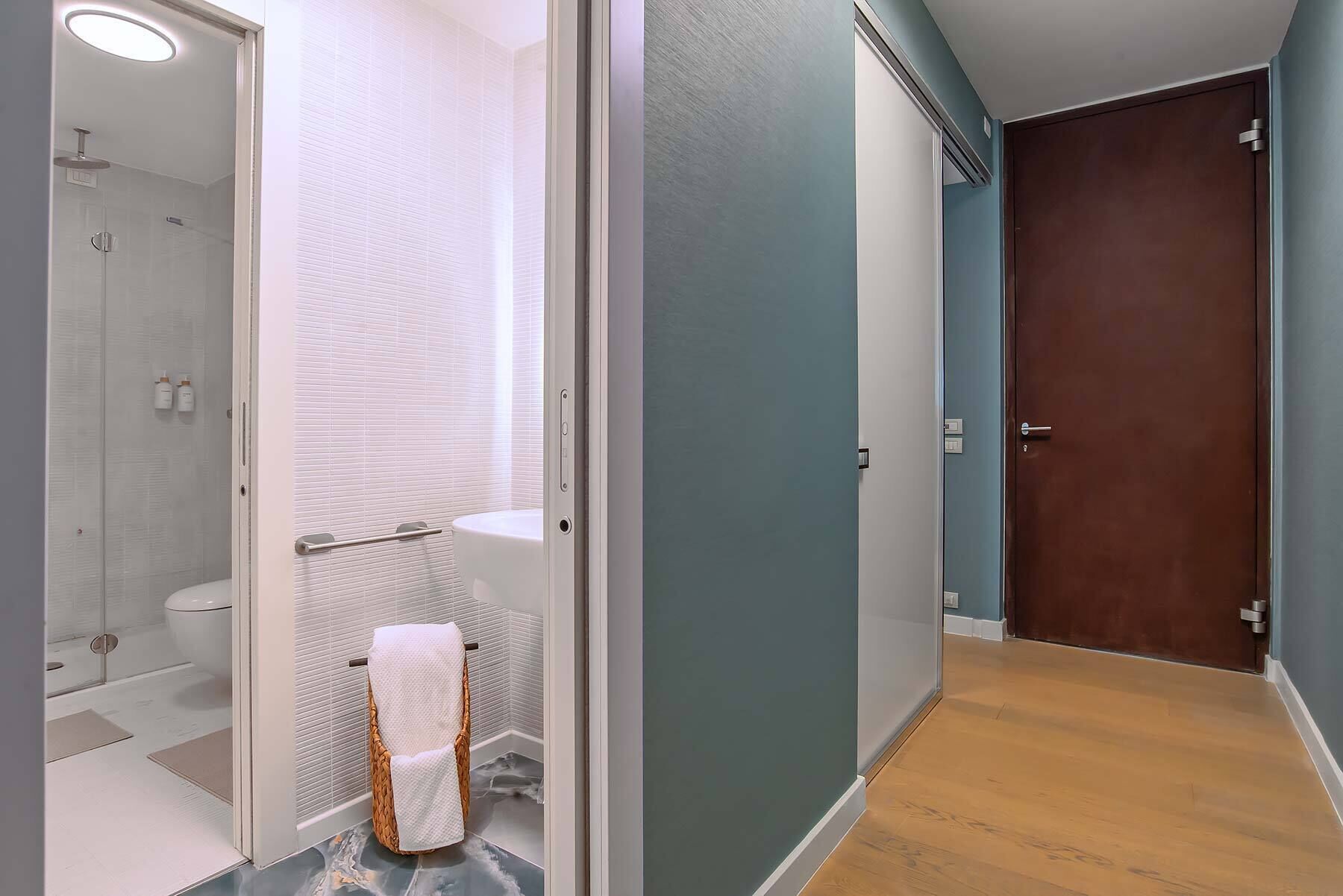 A bathroom with a glass shower enclosure, a toilet, and a towel rack.