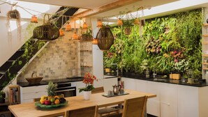 Ett modernt kök med ett matbord i trä, en fruktskål, hängande blomkrukor och en vertikal trädgård.