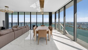 Een modern interieur met een grote eettafel, een bank en uitzicht op de stad en het water.