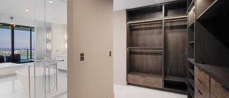 Un baño moderno con cabina de ducha de vidrio, una bañera grande y un vestidor con estanterías de madera.