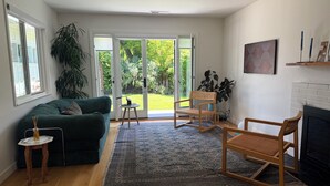 Ein Wohnzimmer mit einem grünen Sofa, einem Holzstuhl, einem kleinen Tisch und einem Kamin.