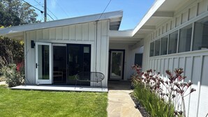 Ein modernes Haus mit Terrasse, einer Glastür und einem kleinen Garten.