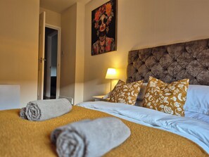 A hotel room with a bed, a nightstand, a lamp, and a door. - City Centre Sanctuary, with free parking. (Worcester)