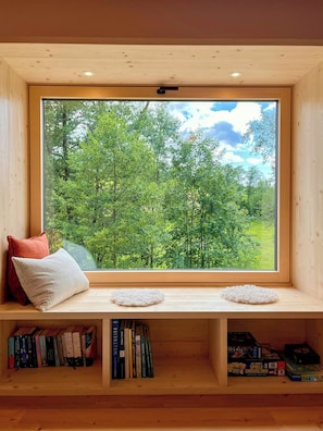 A wooden bench with a view of a forest through a large window. - Hideaway by the stream with countryside views (Jandelsbrunn)