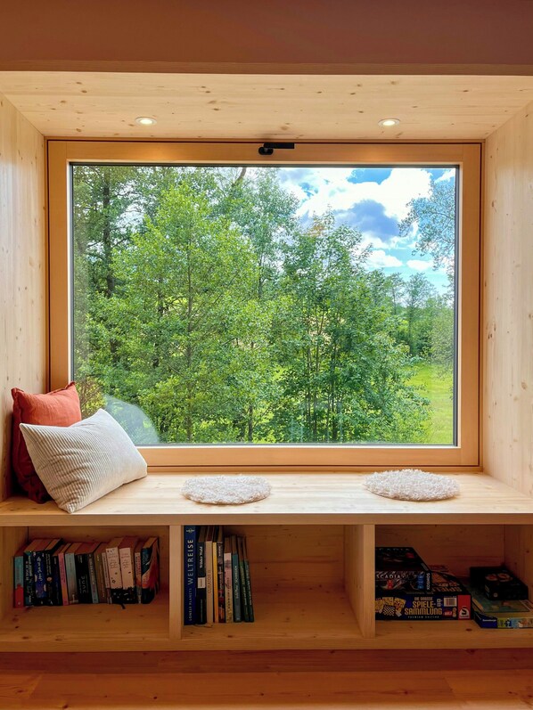 A wooden bench with a view of a forest through a large window. - Hideaway by the stream with countryside views (Jandelsbrunn)