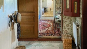 Un interior tradicional con una escalera de madera, una araña y un tapiz estampado.