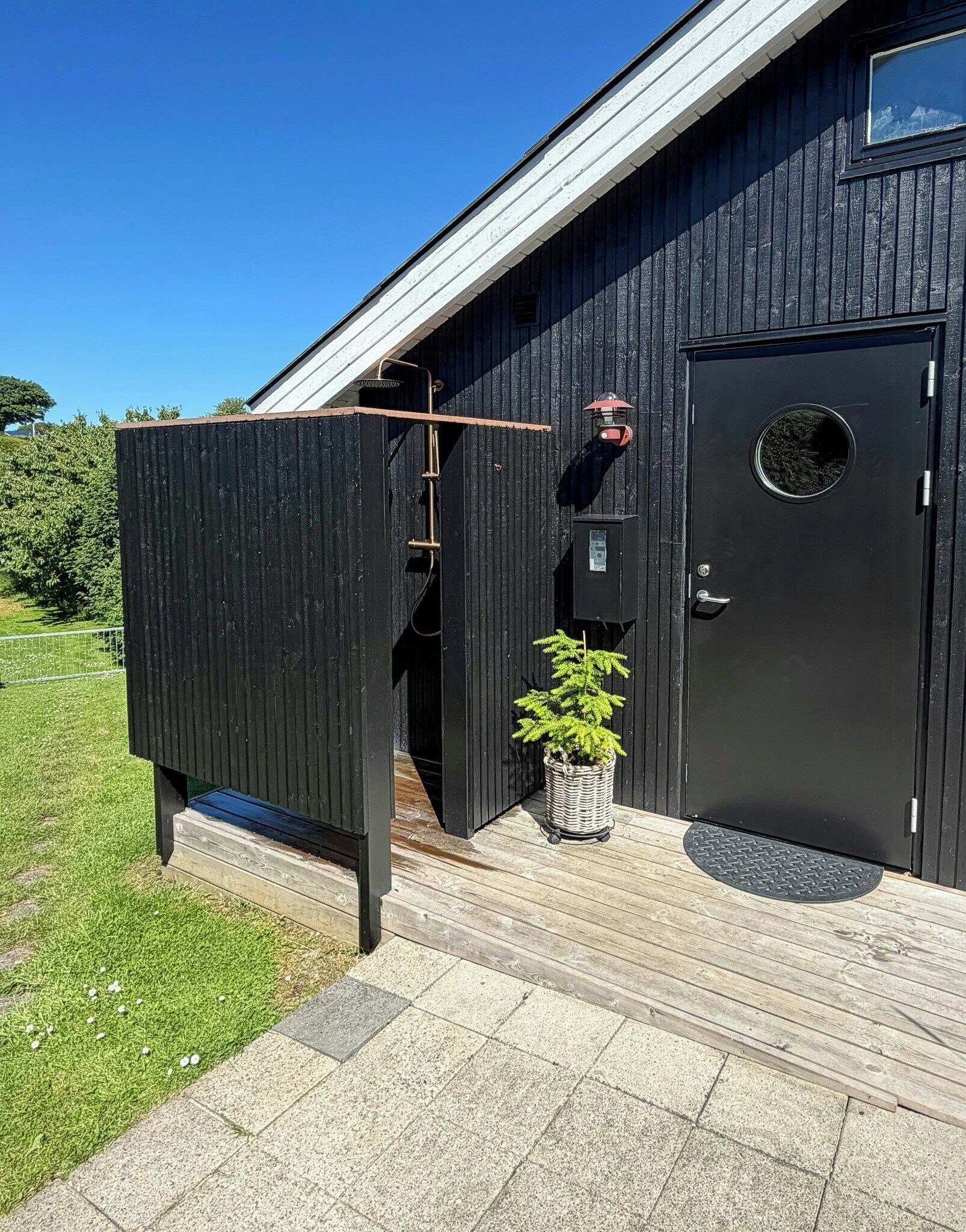 Un edificio in metallo nero con una porta, una finestra e un'apertura circolare.