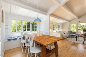 Ein geräumiges Zimmer mit einem Holzespeisetisch, weißen Stühlen und einem großen Fenster.