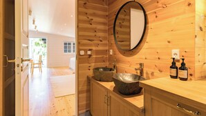 A wooden interior with a large round mirror, two sinks, and a door leading to a bright room. - Log cabin with pool near Tisvilde (Vejby)