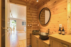 A wooden interior with a large mirror, a stone basin sink, and a wooden cabinet. - Log cabin with pool near Tisvilde (Vejby)