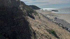 A beach with a rocky cliff, a clear sky, and the sun shining. - Log cabin with pool near Tisvilde (Vejby)