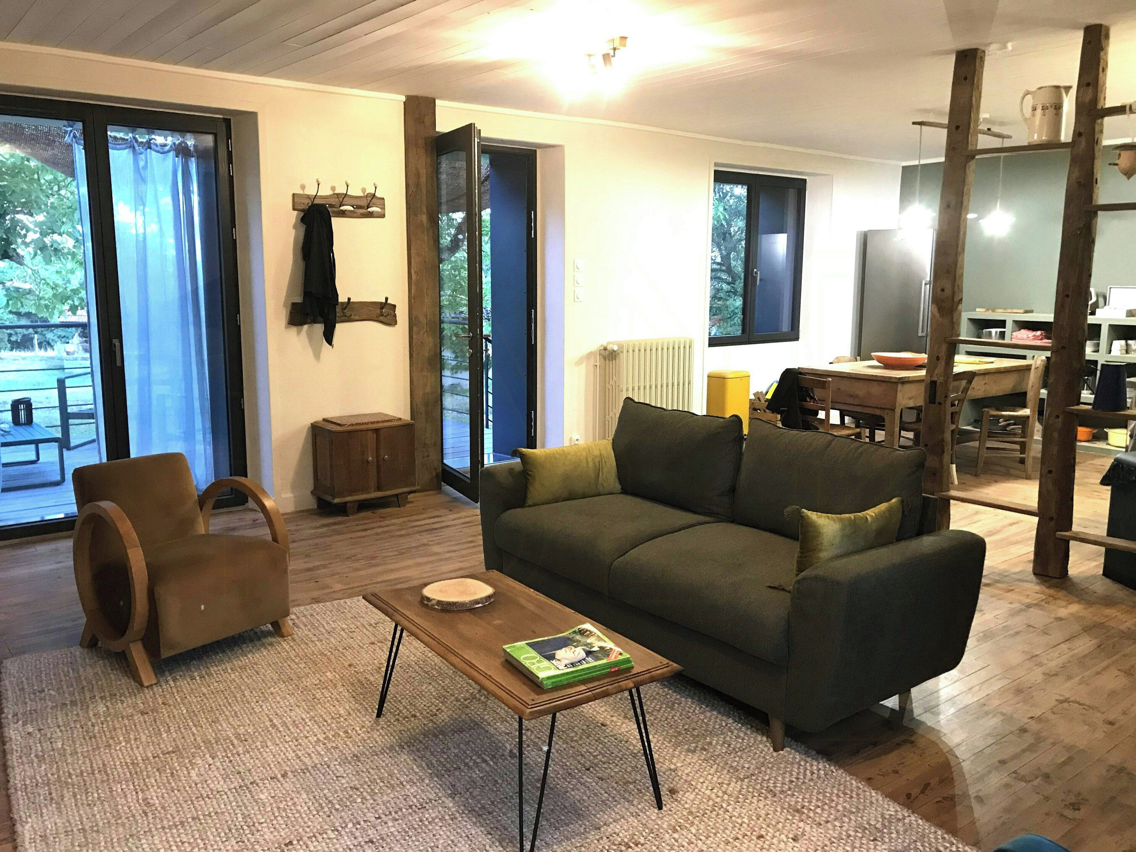 A living room with a sofa, armchair, coffee table, and a dining area with a table and chairs.