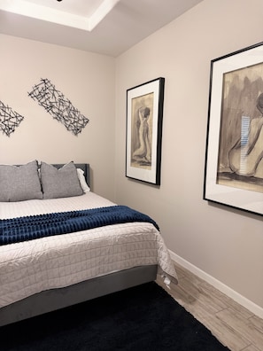 A bedroom with a bed, a dark blue throw blanket, and three framed artworks on the wall. - Modern 1-bedroom apartment with AC in charming Edinburg (Edinburg)