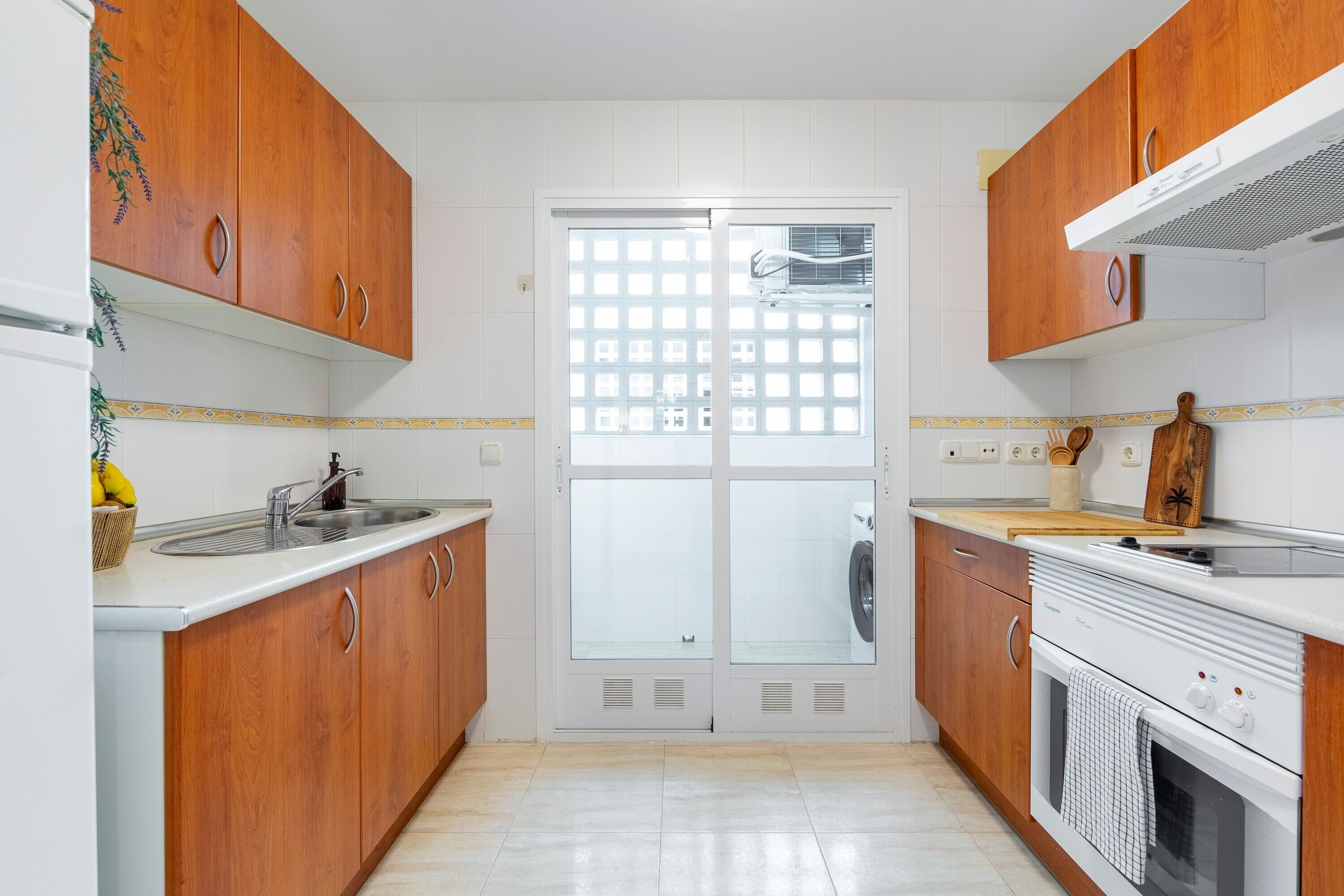 Una cocina con armarios de madera, un lavamanos, una estufa y una ventana con diseño de celosía.