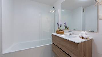 Een moderne badkamer met een douchecabine van glas, een houten wastafelmeubel en een grote spiegel.