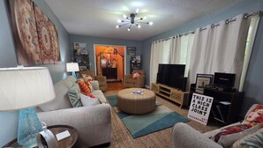 A living room with a sofa, ottoman, TV, and a sign indicating a high-class joint.